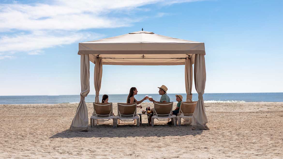 family relaxing in beach cabana