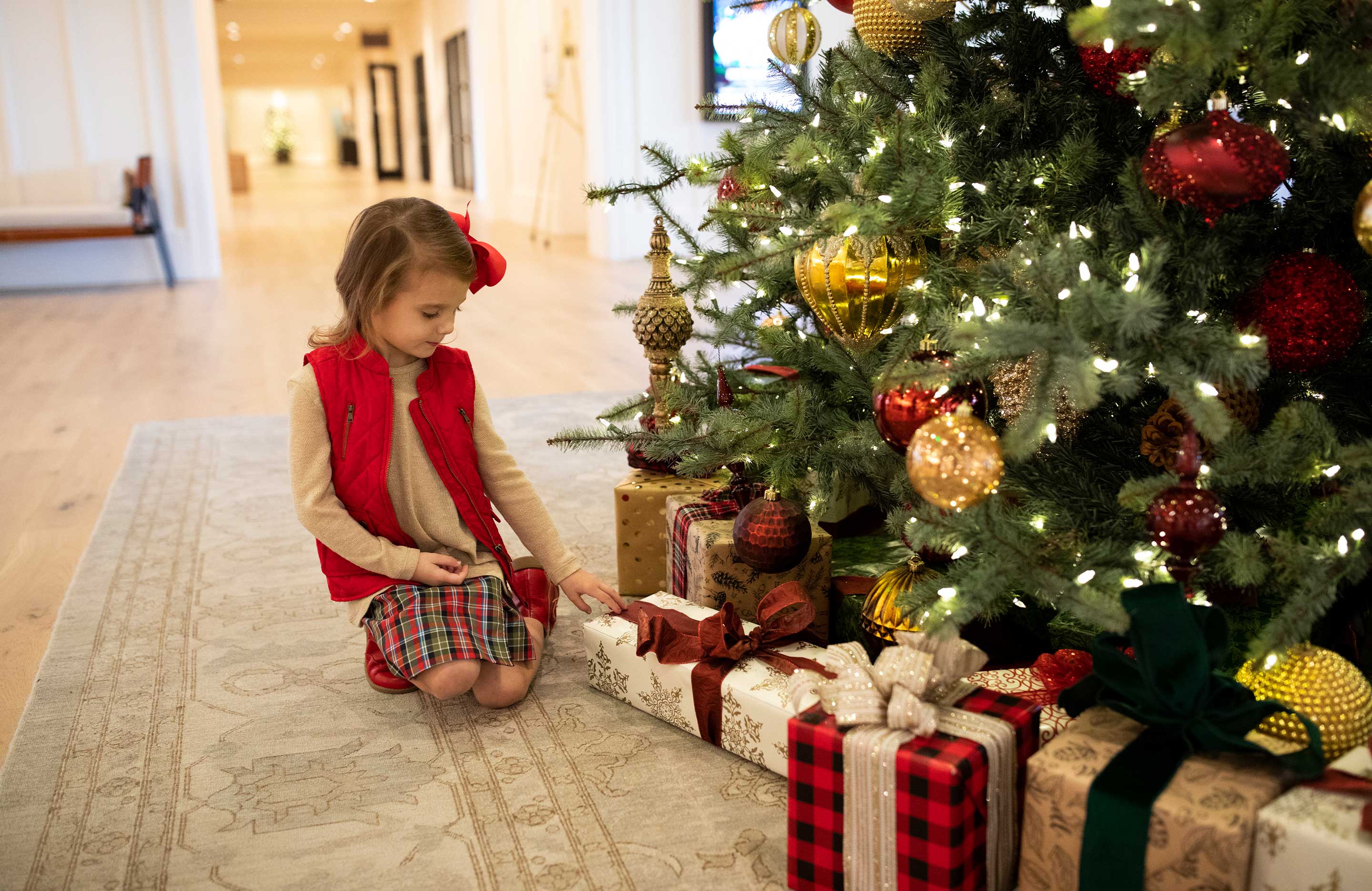 Little girl sitting by the Christmas tree