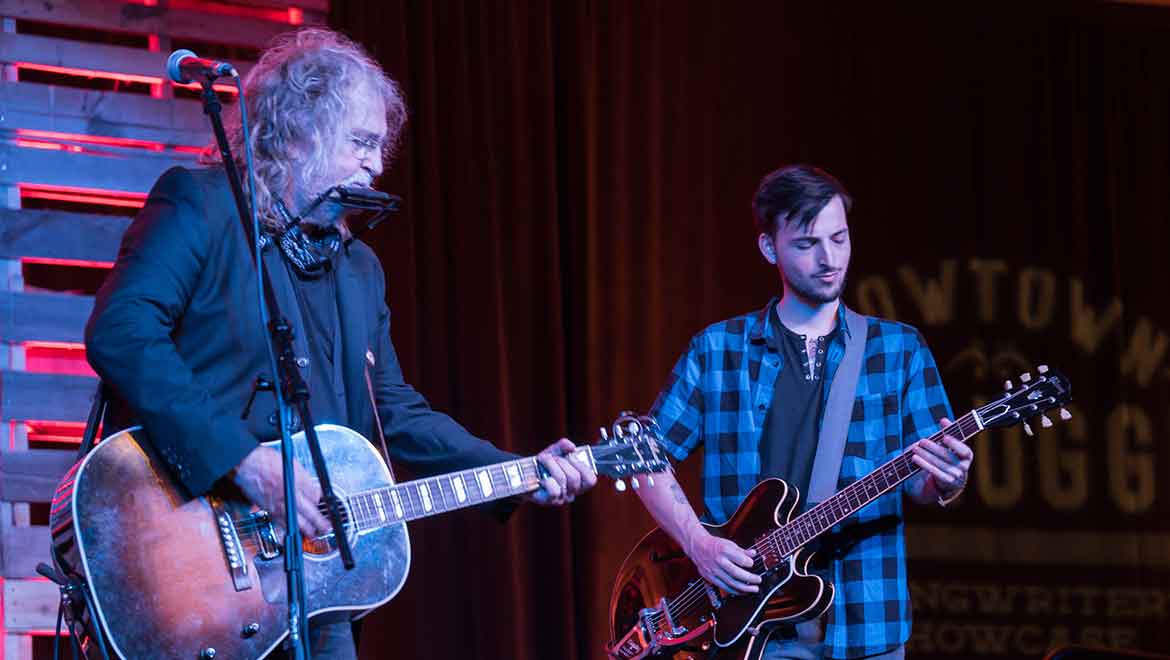 Men playing guitars on stage