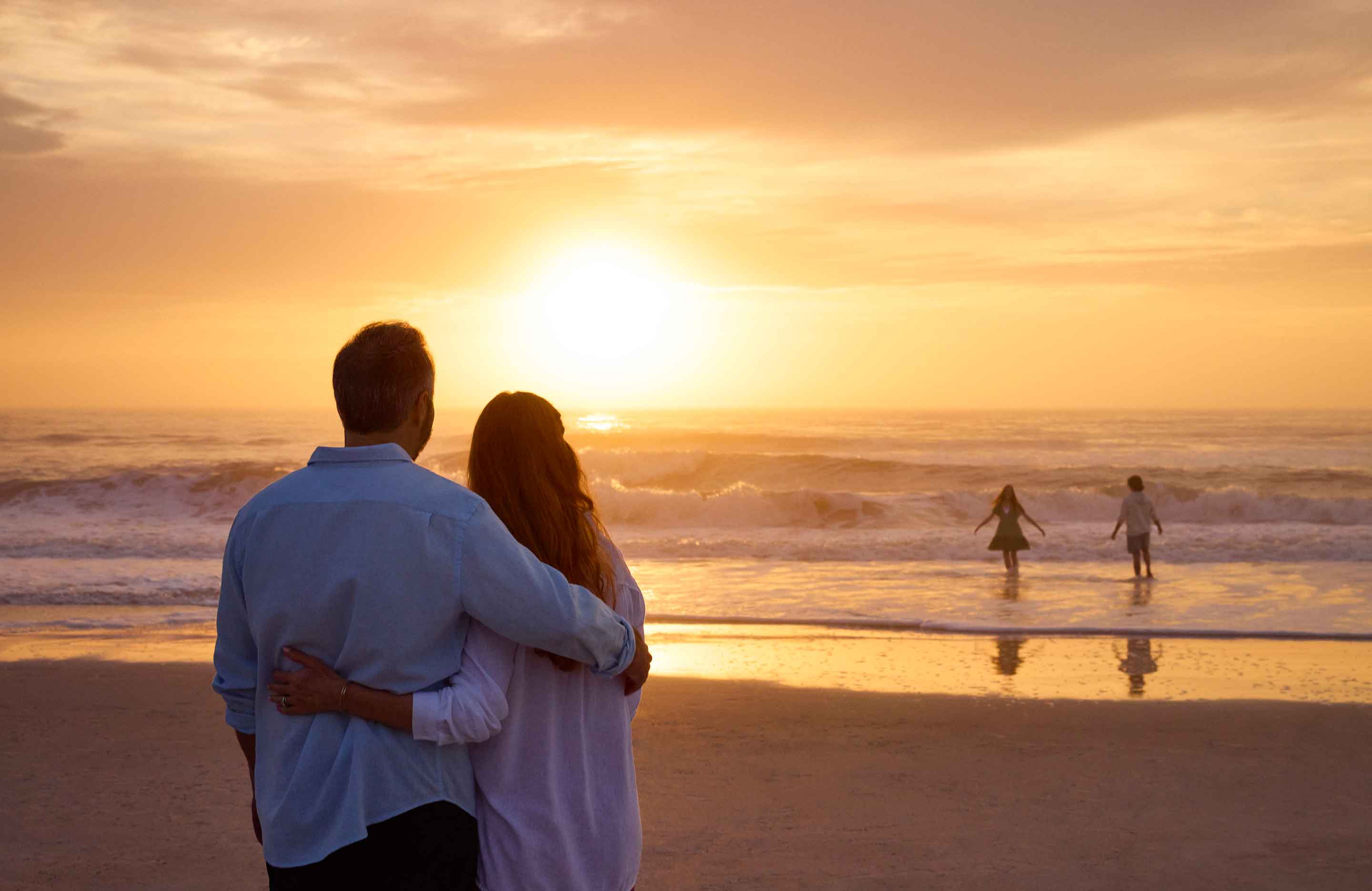 Couple looking at the sunset on the beach.