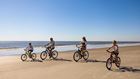 Family riding bikes on the beach