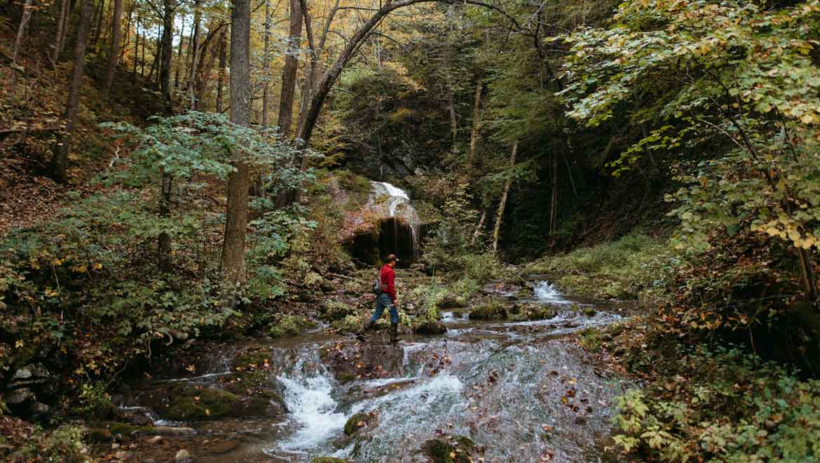 Man walking across a creek 