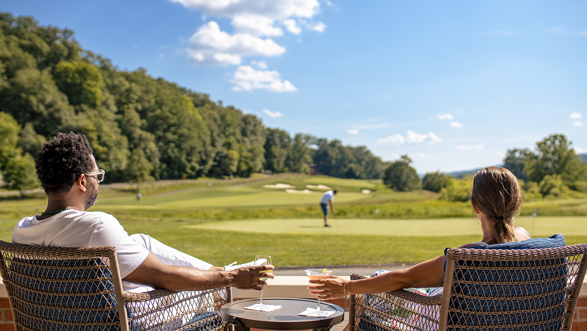 Couple watching golfer on the golf course.