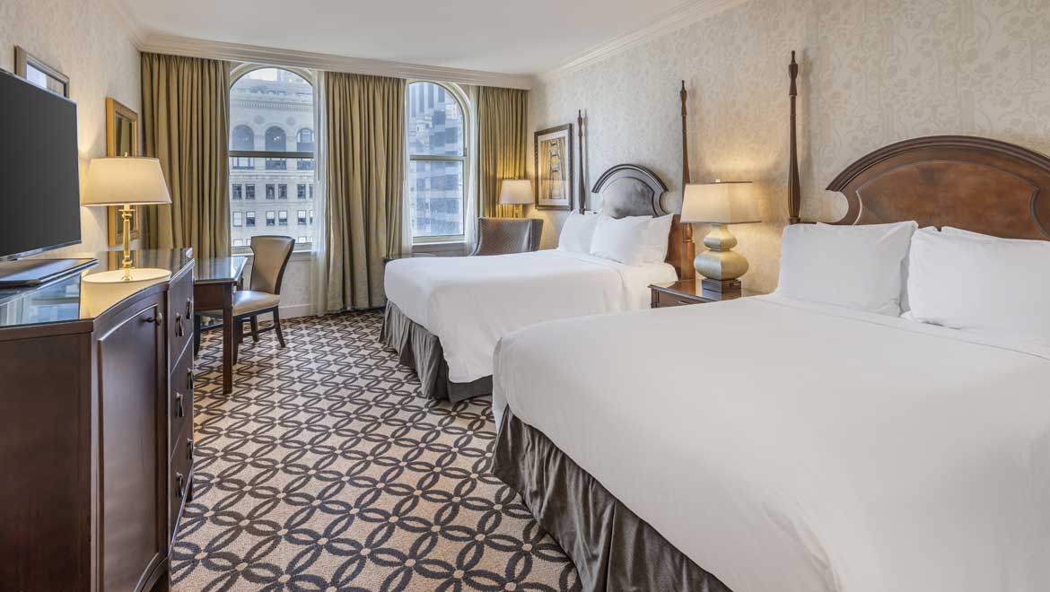 Two queen beds in room with large windows.