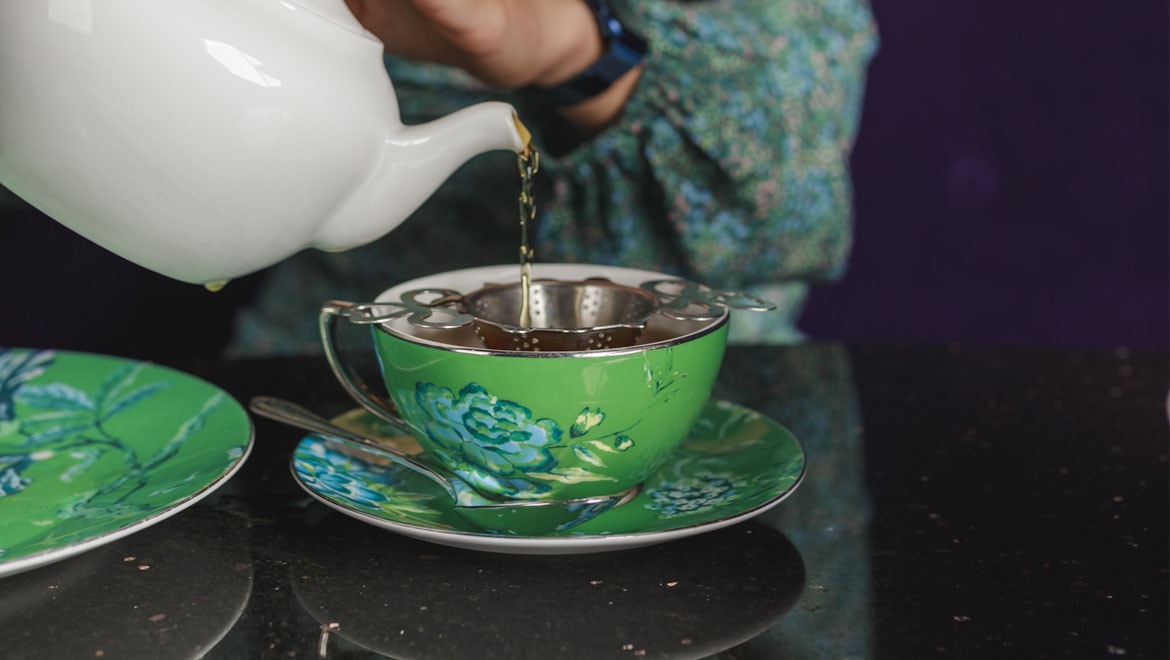 Tea being poured from a kettle into a cup.